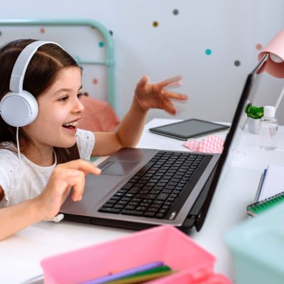 Happy little girl studying from home with laptop